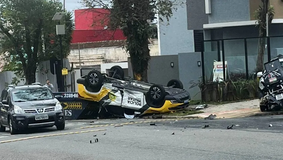 Na imagem, viatura da PMPR está capotada, com rodas para cima, em rua de Curitiba.