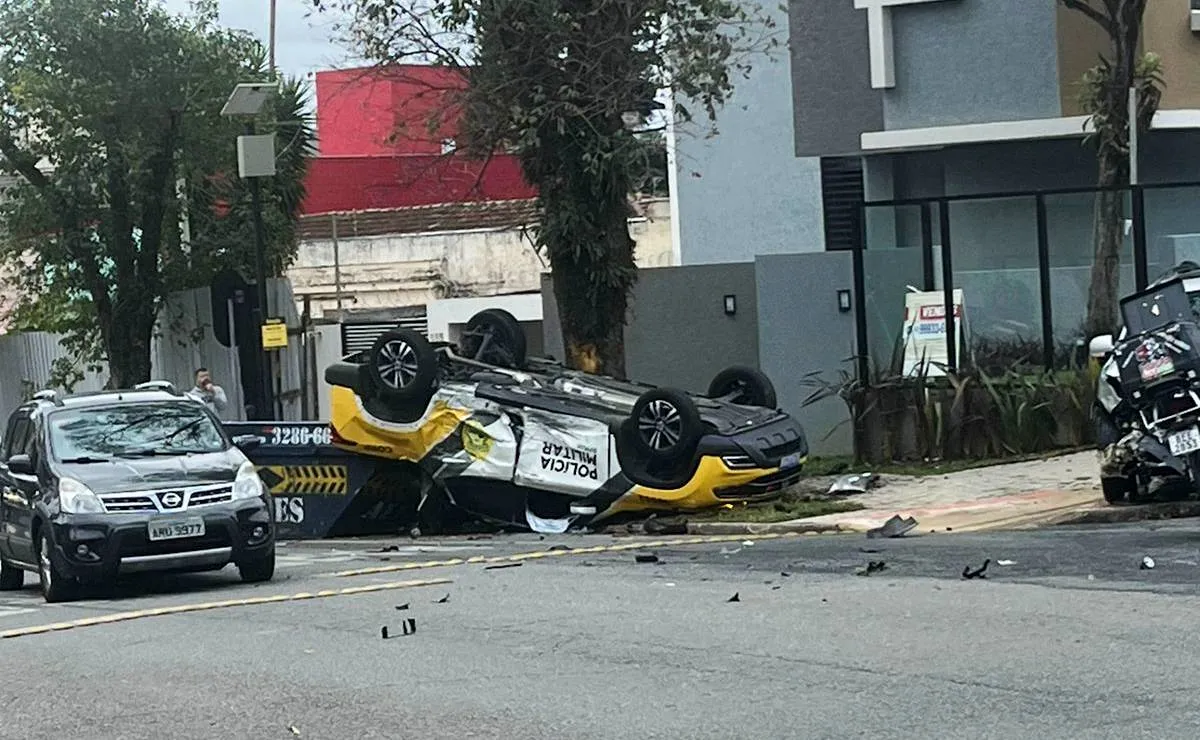 Na imagem, viatura da PMPR está capotada, com rodas para cima, em rua de Curitiba.