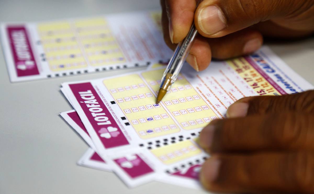 Imagem mostra uma aposta da Lotofácil, com números sendo marcados pelo apostador com uma caneta.