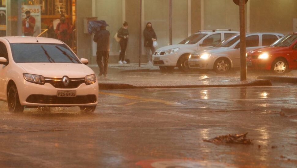 Imagem mostra um carro em meio a um temporal a noite em Curitiba.