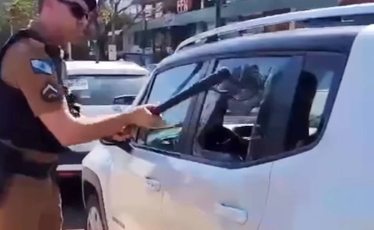 Imagem mostra um policial quebrando o vidro de um carro no Paraná
