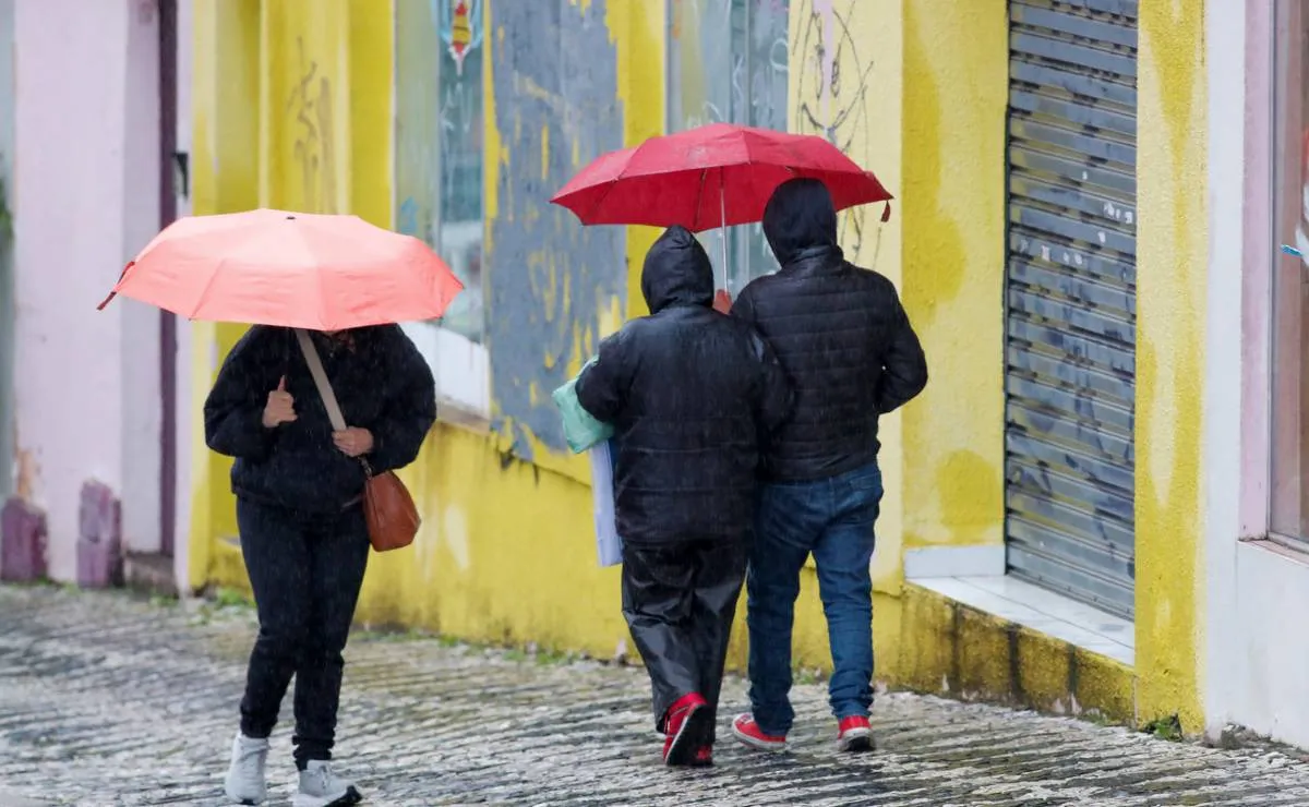 Imagem mostra curitibanos com guarda chuva num dia de muito frio.
