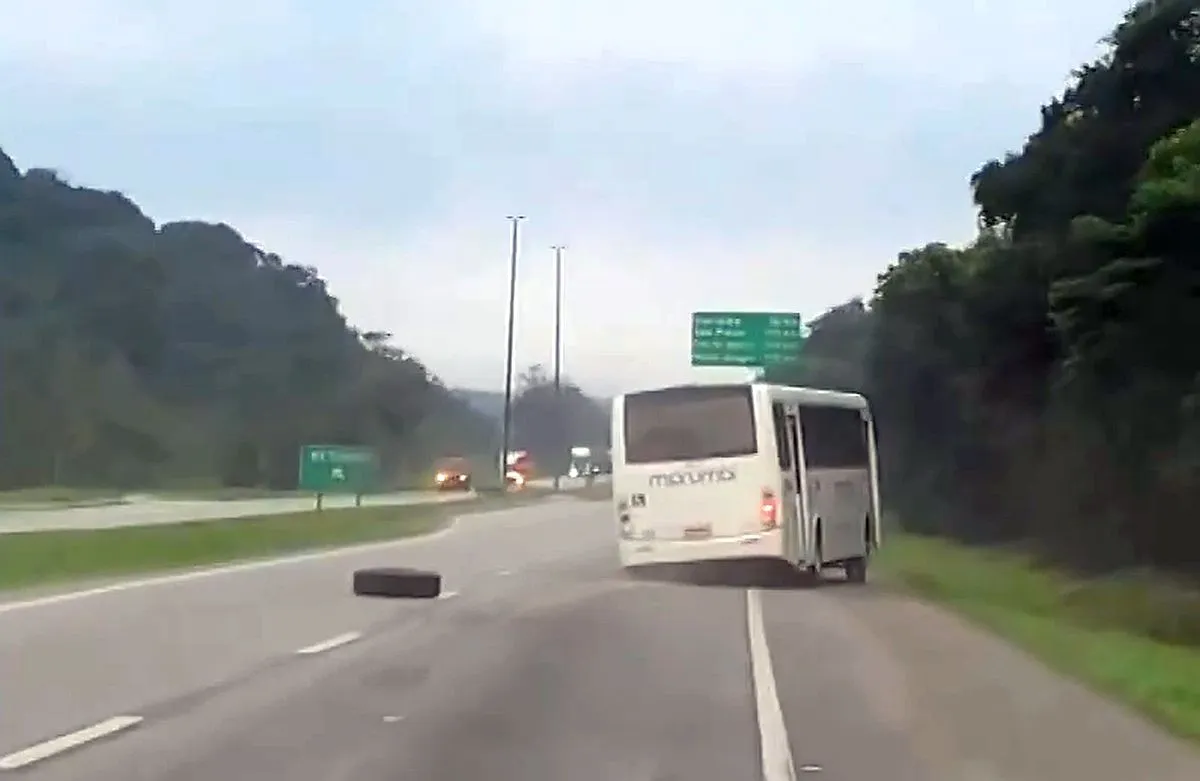 Imagem mostra o ônibus no meio da rodovia, com a roda caída ao seu lado