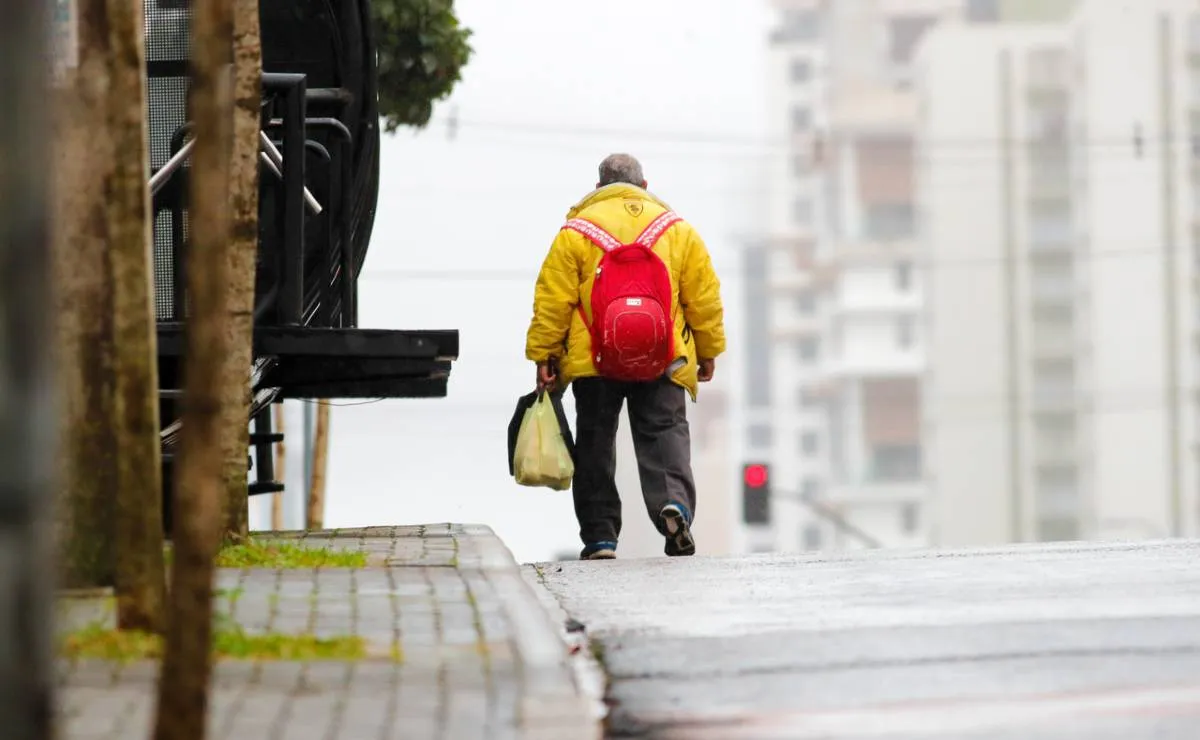 Homem vestindo jaqueta amarela para se proteger do frio em Curitiba.