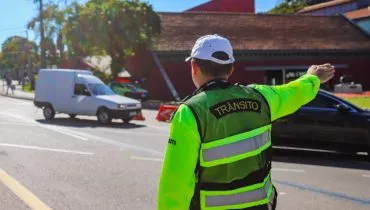 Agente de trânsito orienta motoristas em rua de Curitiba.