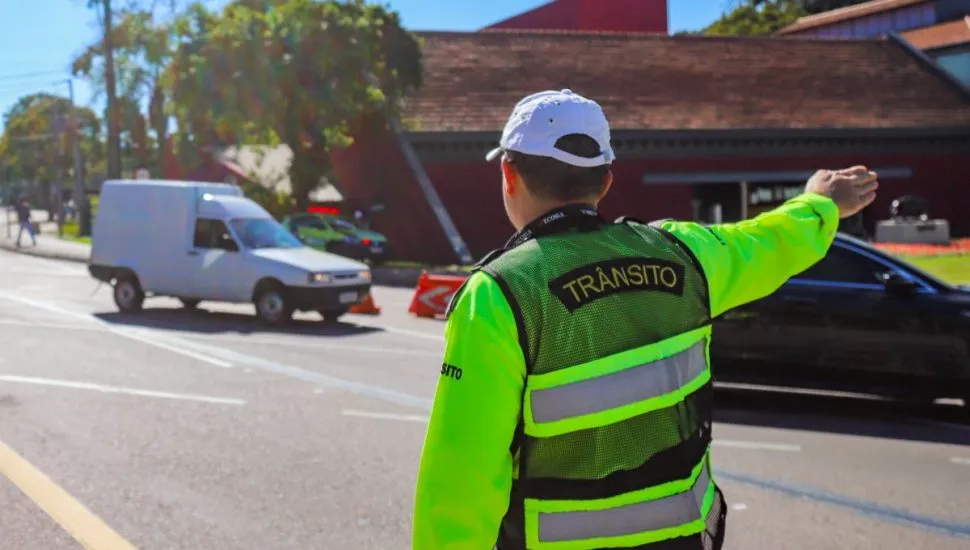 Agente de trânsito orienta motoristas em rua de Curitiba.