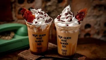 imagem mostra dois copos cheios de milkshake, coberto com chantily e pedaçõs de bacon