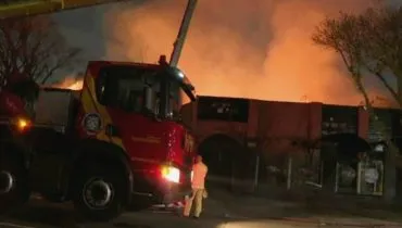 Imagem noturna mostra um caminhão dos Bombeiros jogando água em um prédio em chamas.