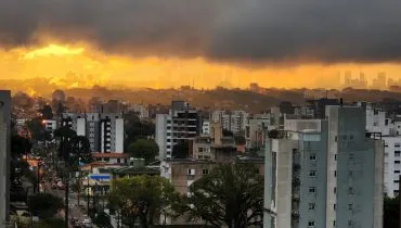 Imagem mostra uma nuvem pesada e faixa iluminada pelo sol, num fim de tarde em em Curitiba.