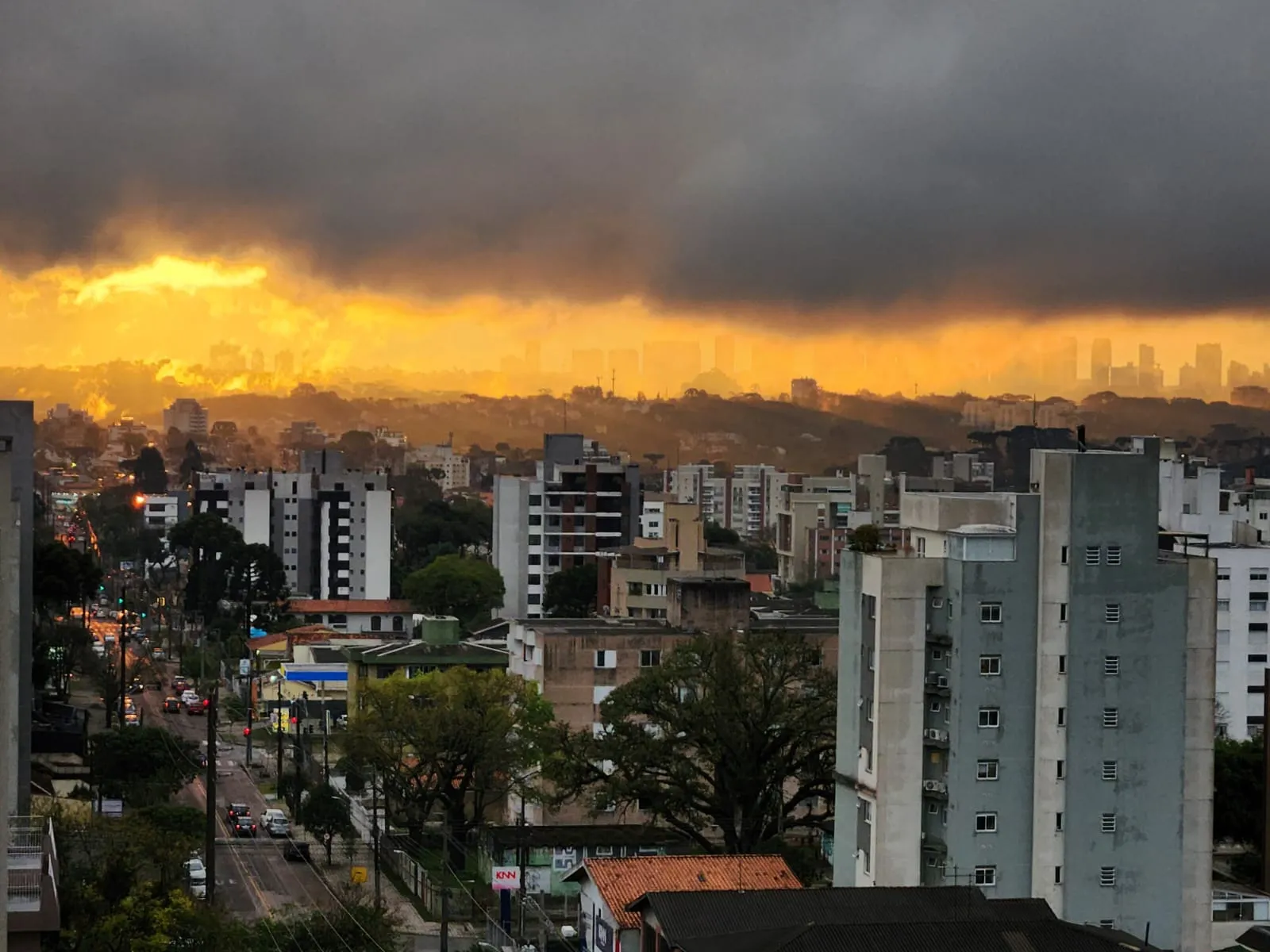 Imagem mostra uma nuvem pesada e faixa iluminada pelo sol, num fim de tarde em em Curitiba.