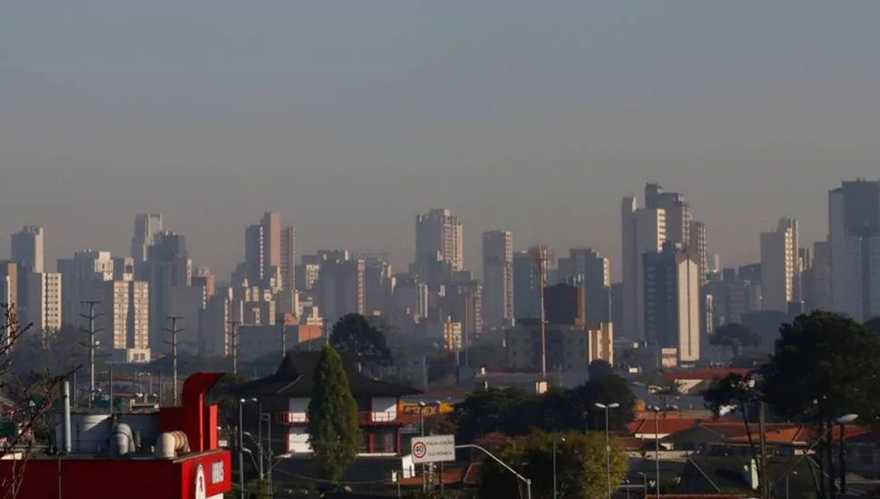 Imagem mostra prédios de Curitiba com uma linha de poluição no horizonte.