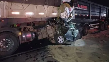 Imagem noturna mostra um carro esmagado entre dois caminhões na BR-116.