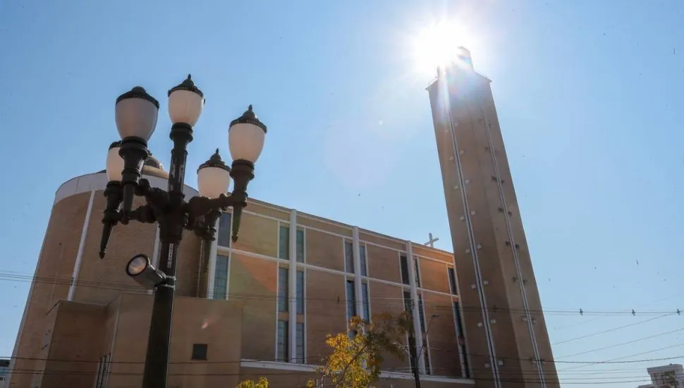 Imagem mostra uma igreja, com detalhe do sol se escondendo atrás de uma das torres.