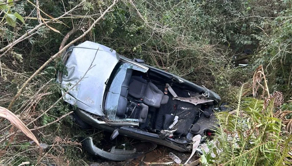 Na imagem, carro destruído no mato, após acidente na rodovia.