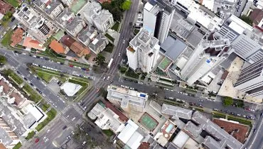 Foto aérea da cidade de Curitiba, com prédios, ruas e carros.