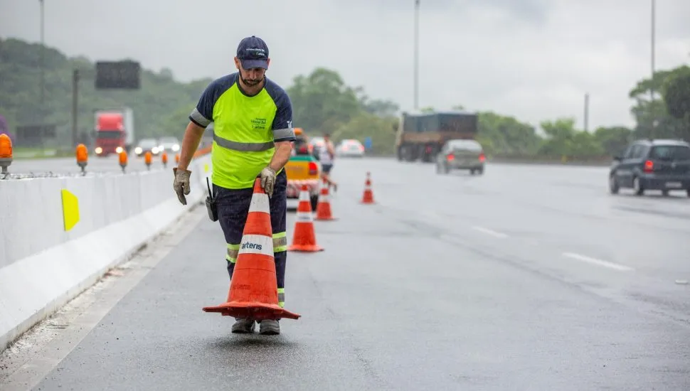 Funcionário da concessionária Arteris Litoral Sul posicionando cones na BR-376.