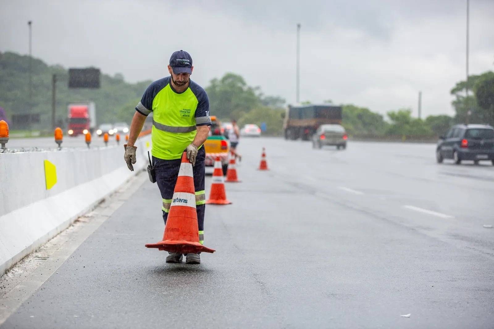 Funcionário da concessionária Arteris Litoral Sul posicionando cones na BR-376.