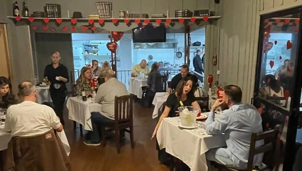 Imagme mostra interior do restaurante, com várias pessoas e pessoas comendo