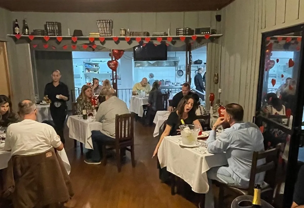 Imagme mostra interior do restaurante, com várias pessoas e pessoas comendo