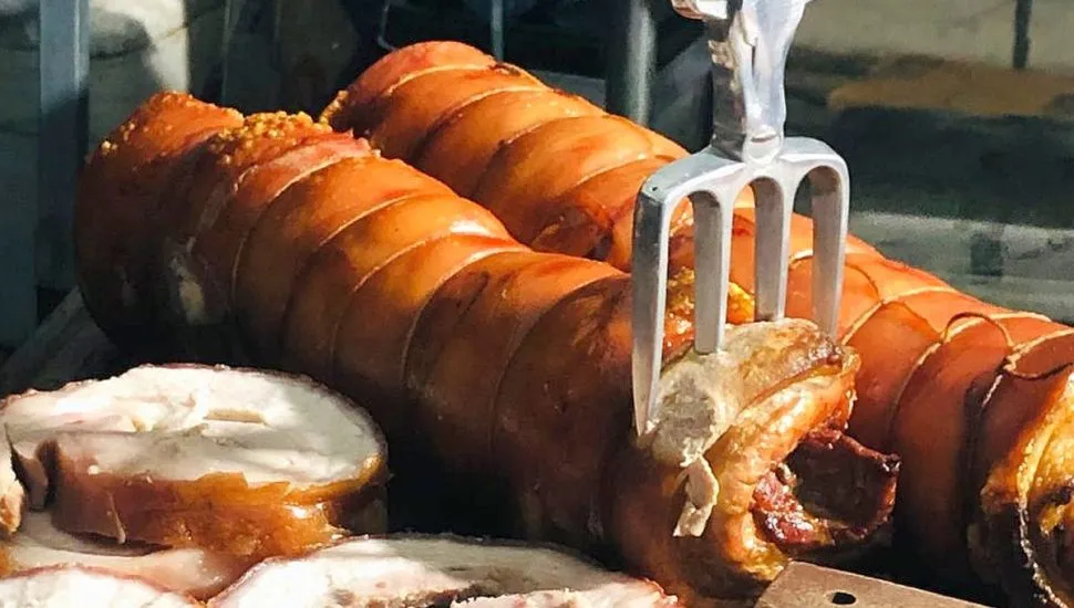 imagem mostra dois pedações grandes de panceta em forma de torresmo de rolo com um carfo espetado.