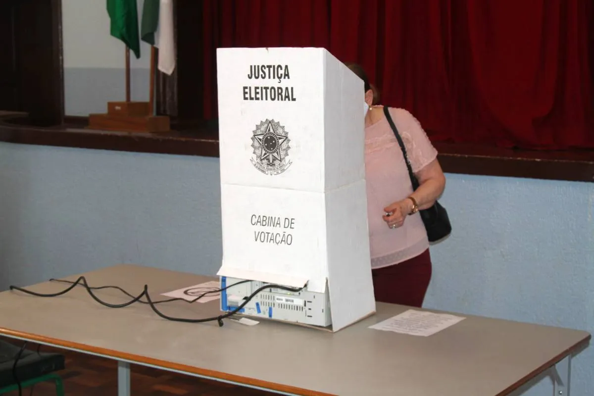 Imagem mostra uma eleitora em uma cabina de votação.