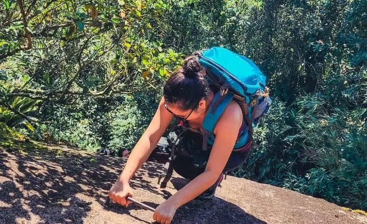 Na imagem, uma pessoa sobe uma escada em uma pedra, durante uma escalada.