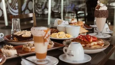 Imagem mostra uma farta mesa de café da manhã, com vários doces e salgados