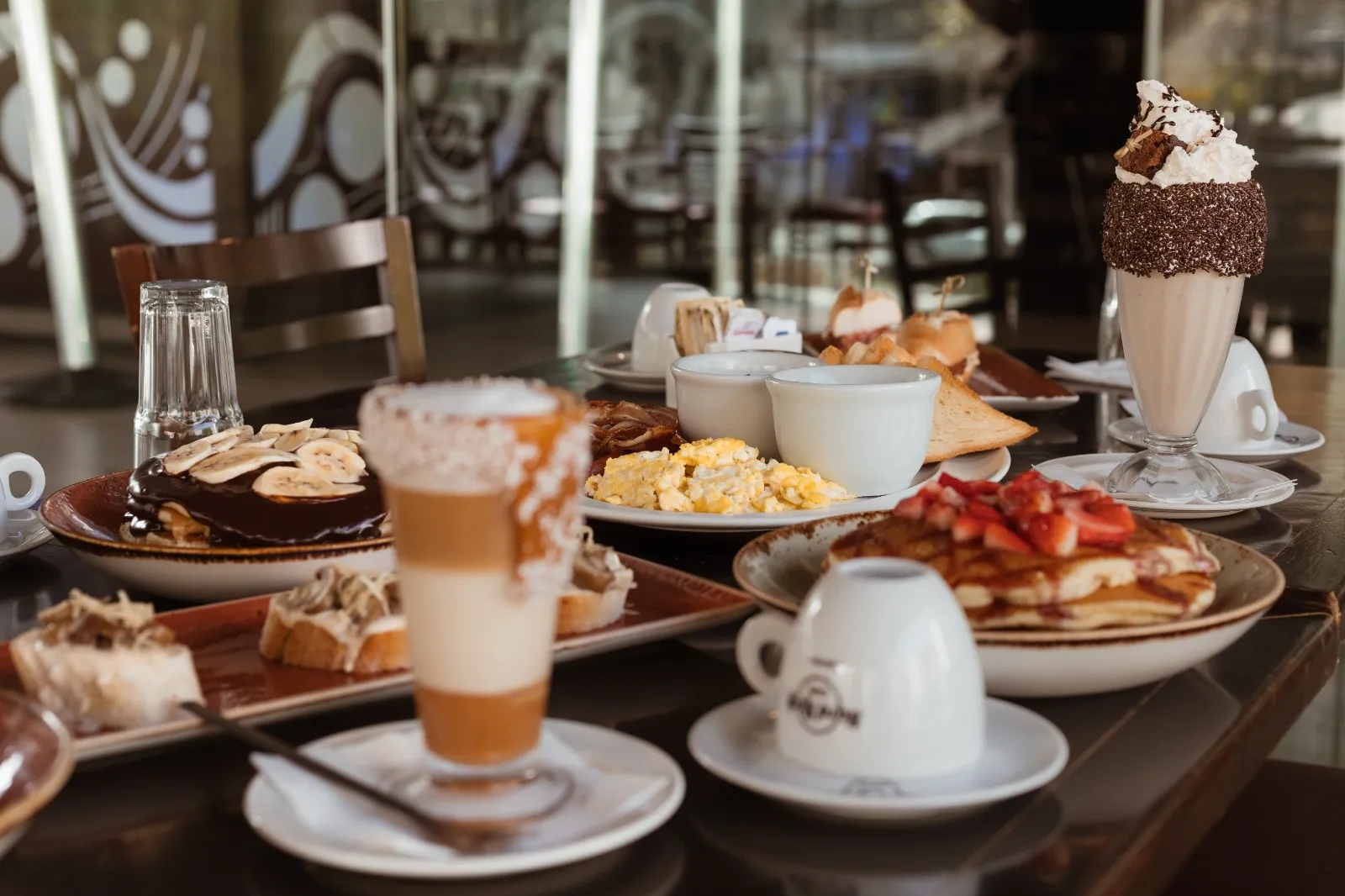 Imagem mostra uma farta mesa de café da manhã, com vários doces e salgados