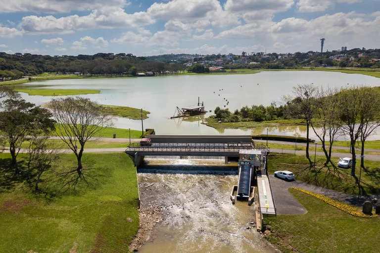 Imagem aérea que mostra parte do Parque Barigui e extenso lago.