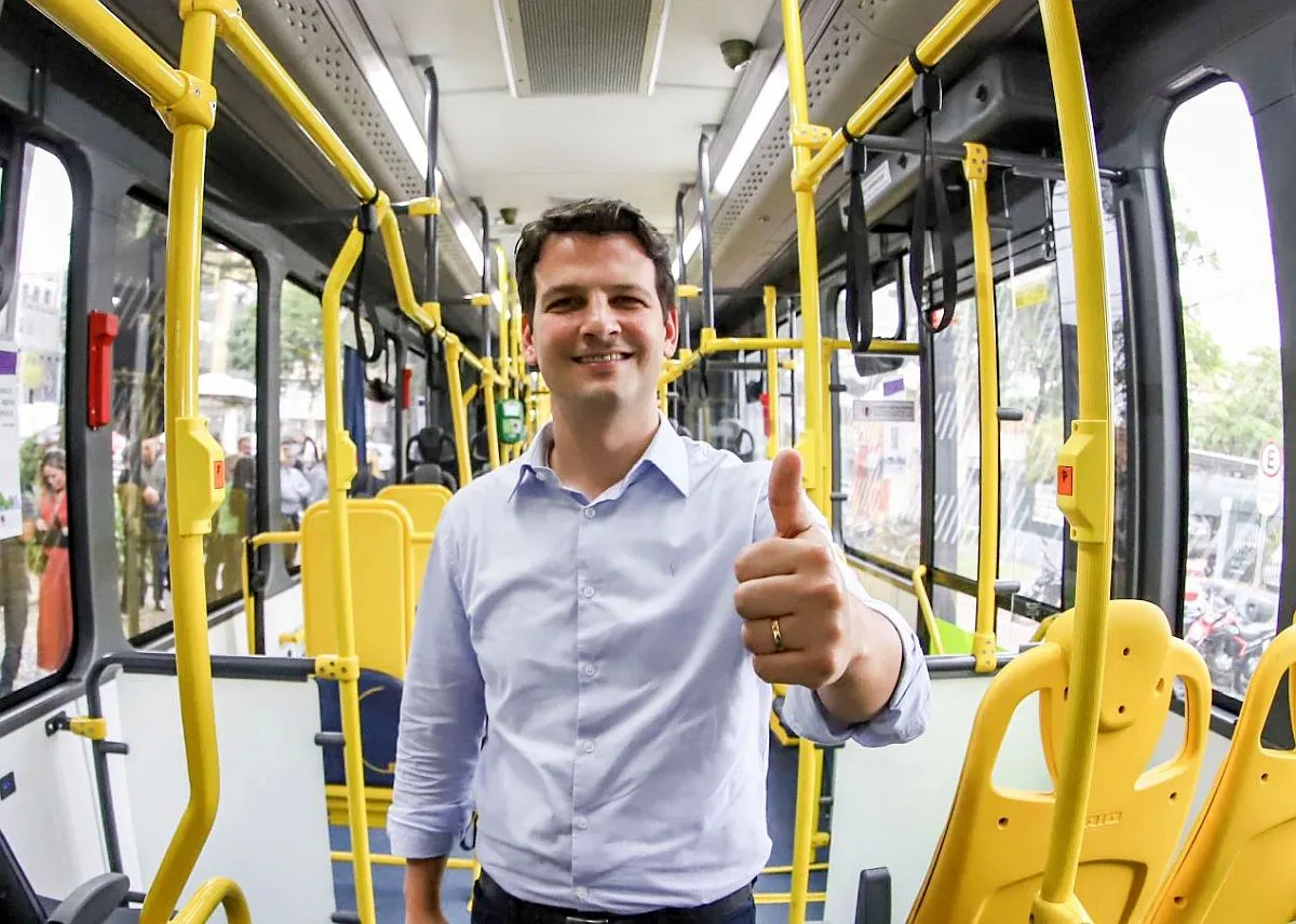 imagem mostra candidato Eduardo Pimentel dentro de um ônibus fazendo sinal de positivo para a câmera