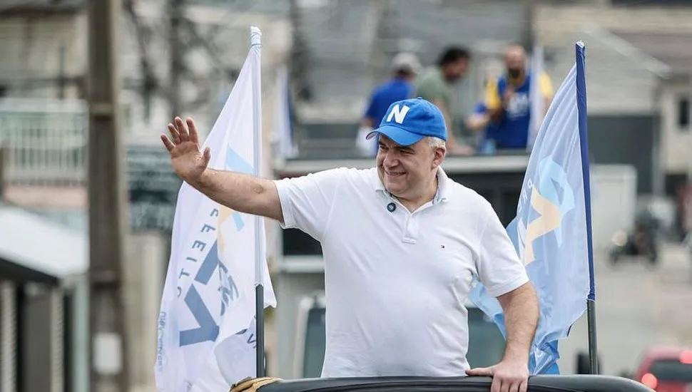 candidato Ney Leprevost faz gestos para pessoas na rua em cima de um jipe