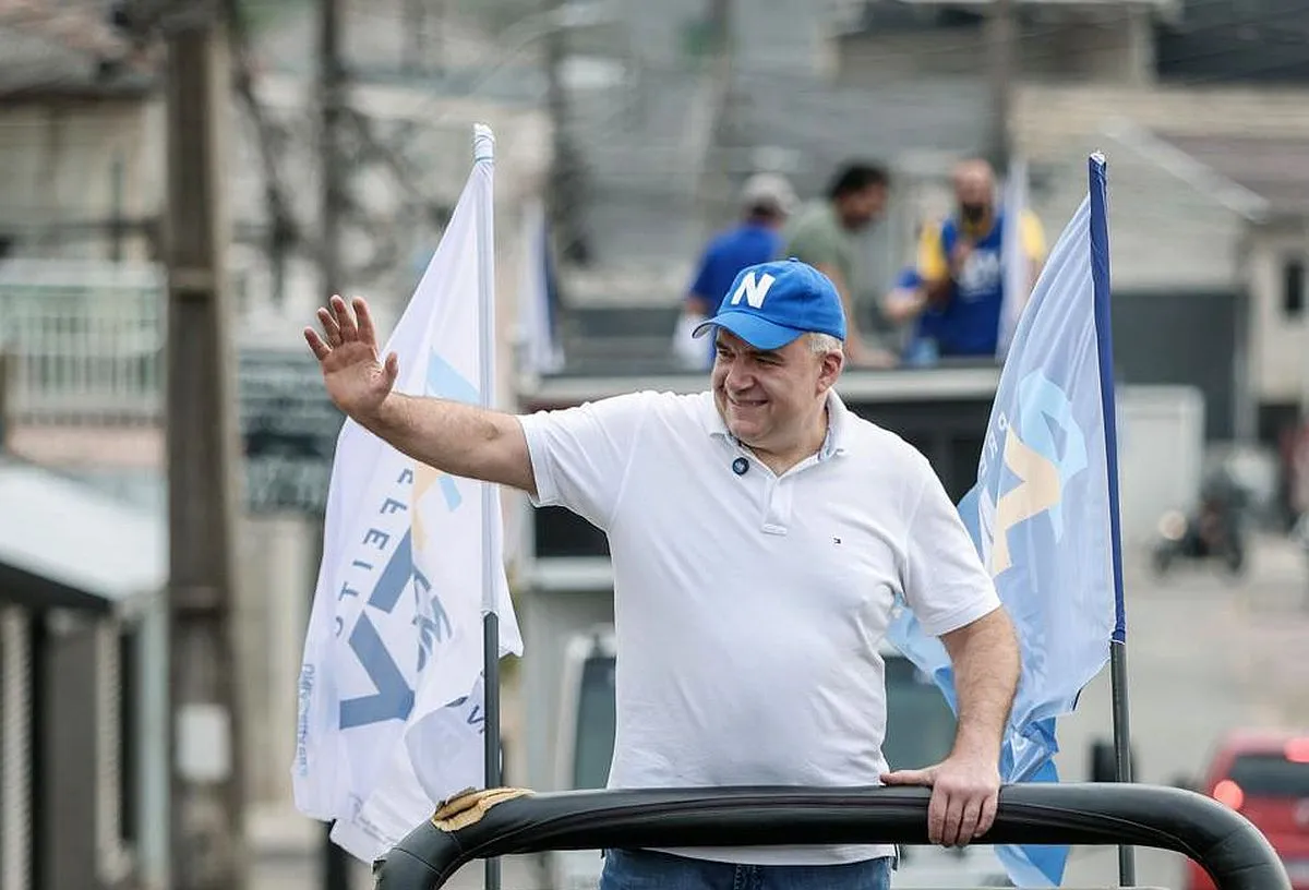 candidato Ney Leprevost faz gestos para pessoas na rua em cima de um jipe