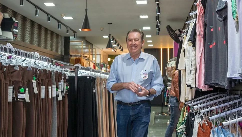 Candidato Luciano Ducci caminha dentro de uma loja de roupas durante campanha.