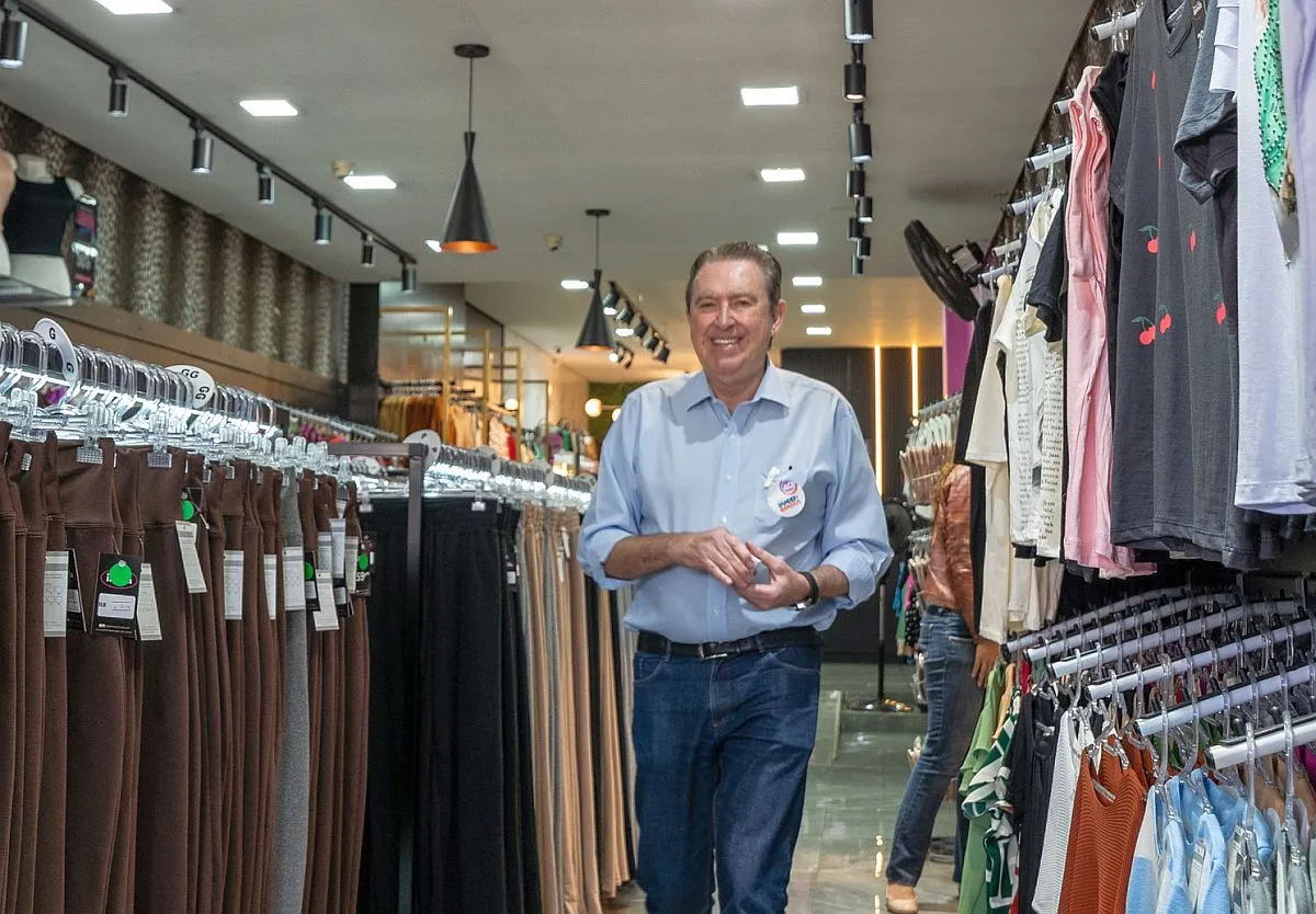 Candidato Luciano Ducci caminha dentro de uma loja de roupas durante campanha.