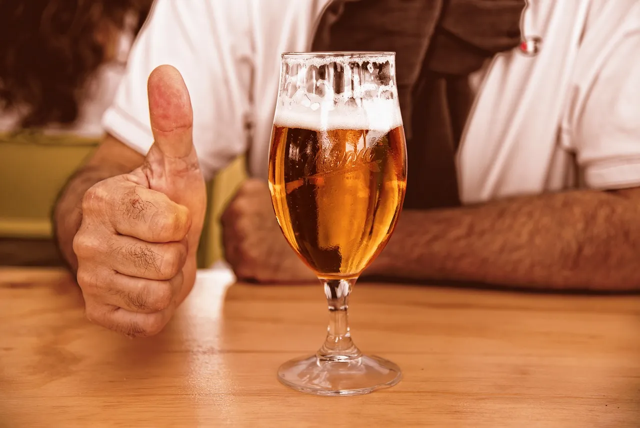 Pessoa com um chope fazendo 'joínha' com a mão.