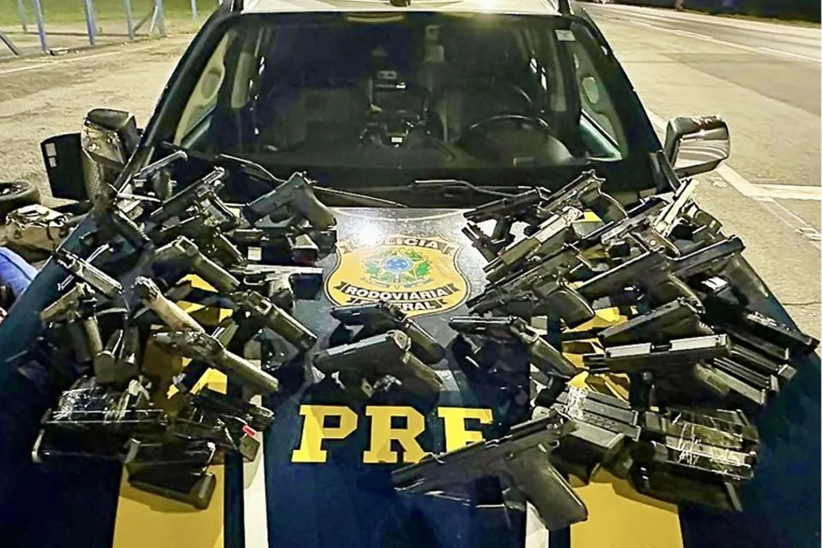 Na imagem, diversas pistolas e carregadores sobre o capô de uma viatura da PRF.