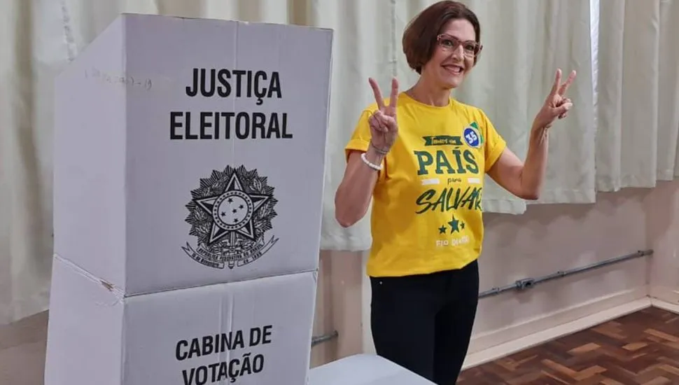 Imagem mostra a candidata Cristina Graeml votando em Curitiba com uma camiseta amarela.