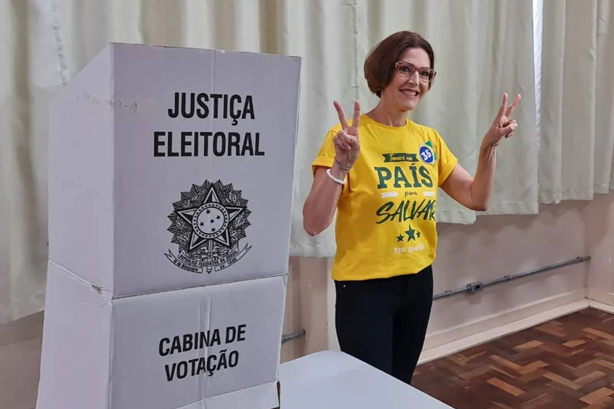 Imagem mostra a candidata Cristina Graeml votando em Curitiba com uma camiseta amarela.