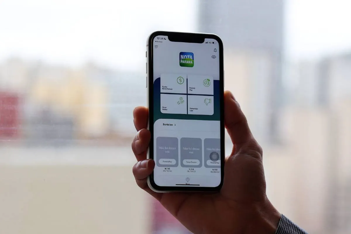 Foto mostra uma pessoa segurando um celular com o aplicativo Nota Paraná aberto.