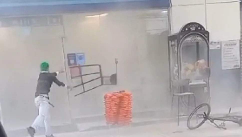 Na imagem, jovem joga uma cadeira contra a porta de vidro de uma loja de conveniência.