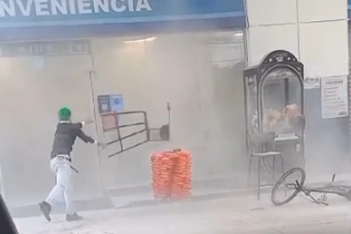 Na imagem, jovem joga uma cadeira contra a porta de vidro de uma loja de conveniência.