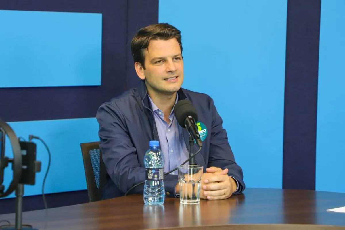 Na imagem, Eduardo Pimentel sentado e com as mãos em uma mesa.