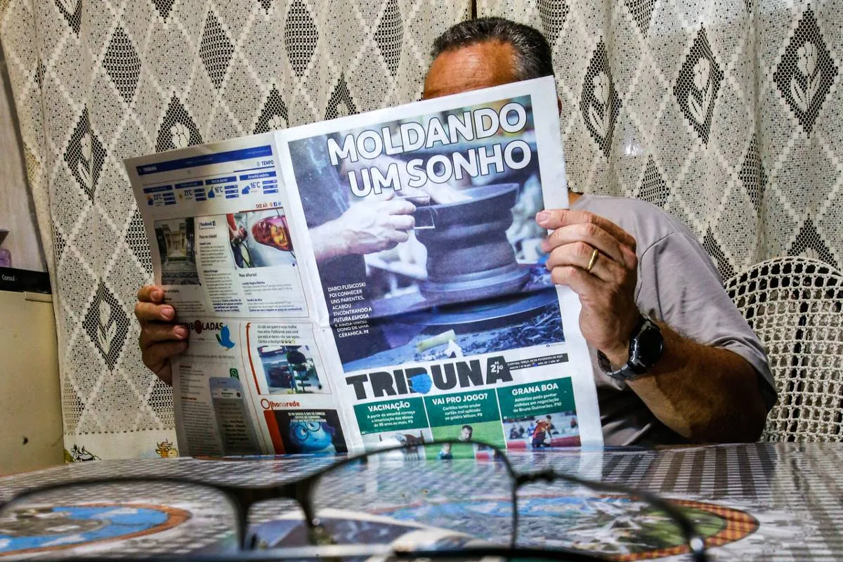 Imagem mostra um homem lendo a versão impressa da Tribuna do Paraná.