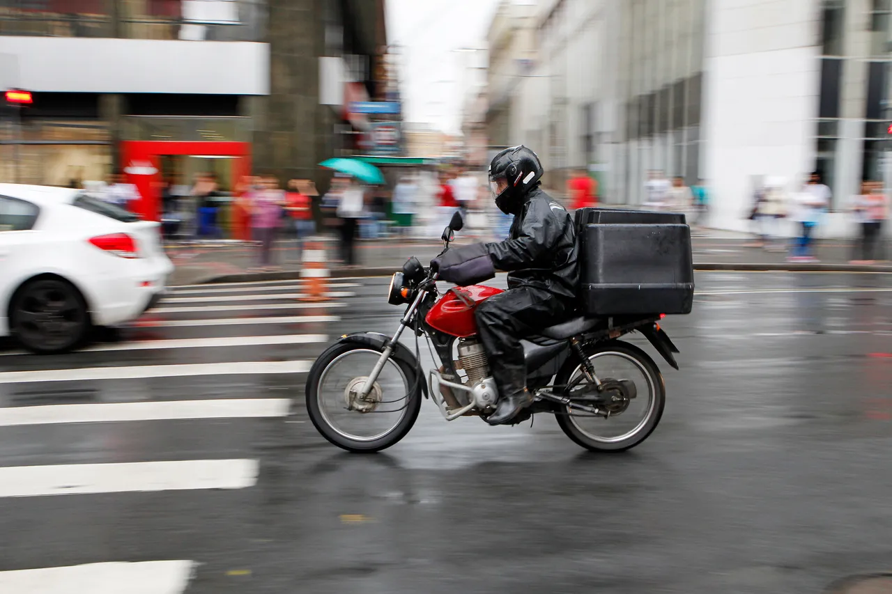 imagem mostra motoqueiro no centro de Curitiba durante um dia de chuva