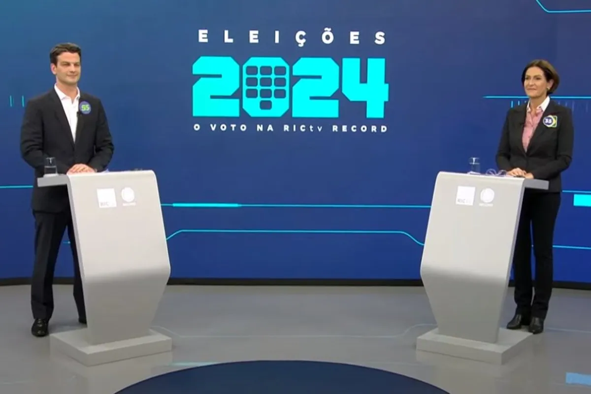 Na imagem, os candidatos Eduardo Pimentel e Cristina Graeml em um estúdio de TV, durante um debate.