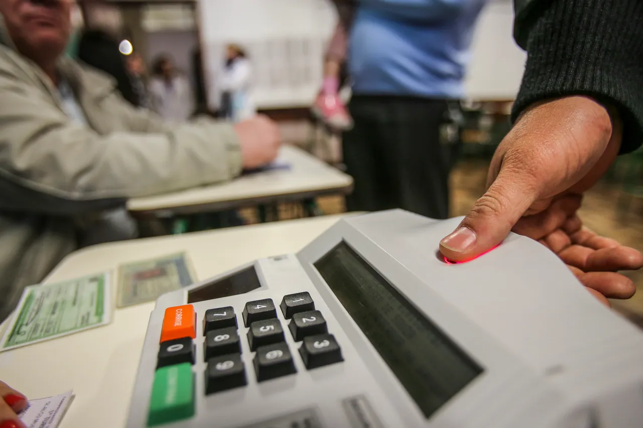 Segundo turno das eleições: Urna Eletrônica com detalhe da mão de um eleitor pelo voto biométrico antes da urna eletrônica