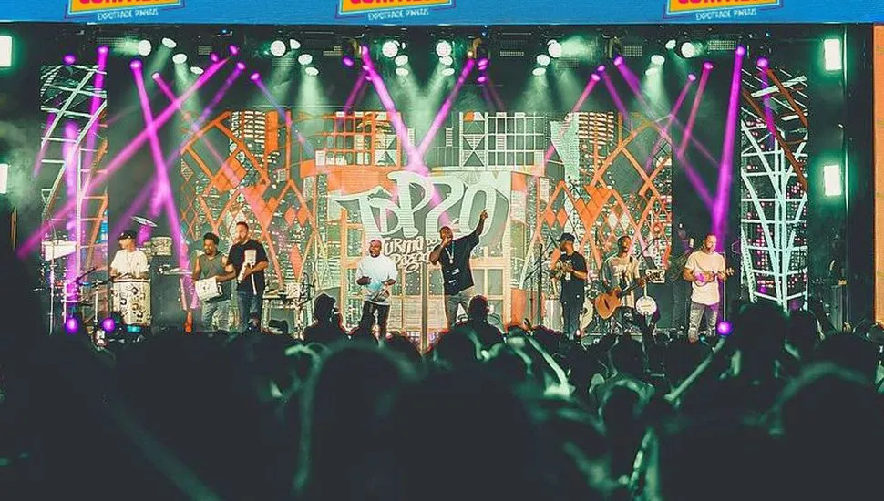 Imagem mostra uma multidão de pessoas acompanhando o show de uma banda de pagode ao fundo, num grande palco do evento anterior do Samba Curitiba