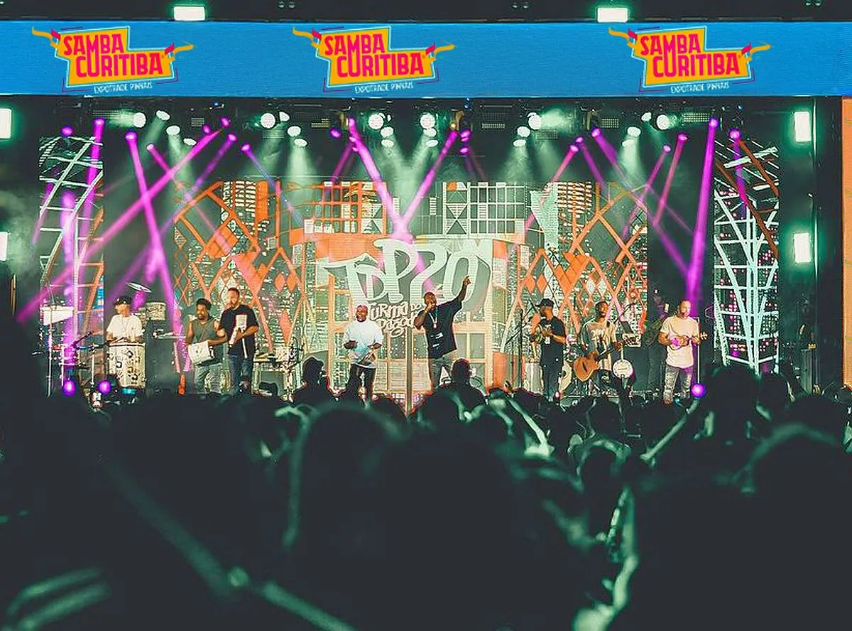 Imagem mostra uma multidão de pessoas acompanhando o show de uma banda de pagode ao fundo, num grande palco do evento anterior do Samba Curitiba