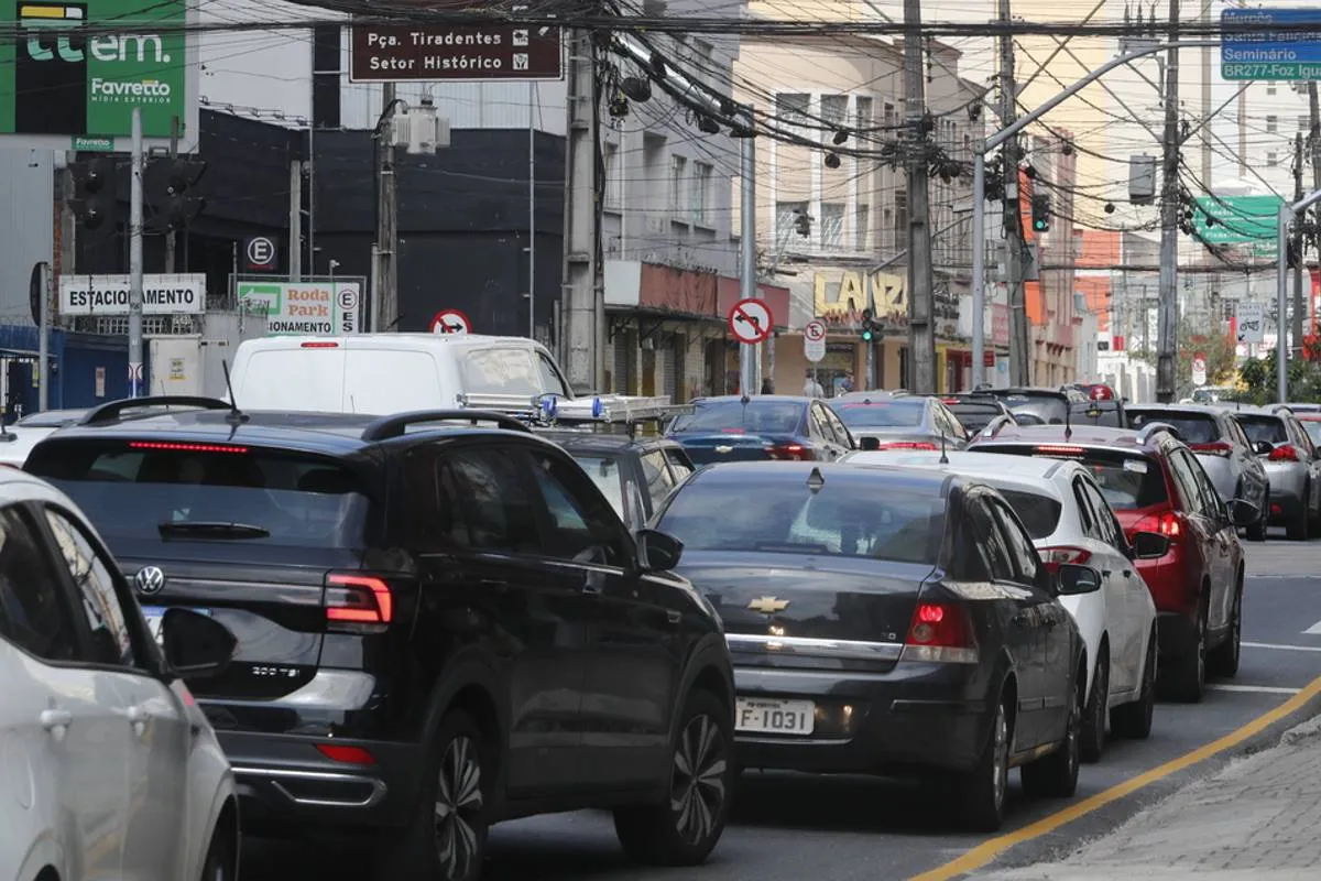 Imagem mostra o transito em Curitiba em um dia de semana. Carros estão em um congestionamento.