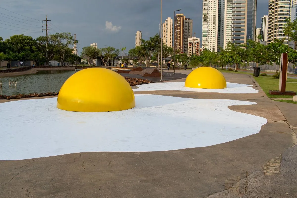 Imagem mostra uma praça, com duas esculturas em forma de ovos fritos, com prédios da cidade de Belém ao fundo